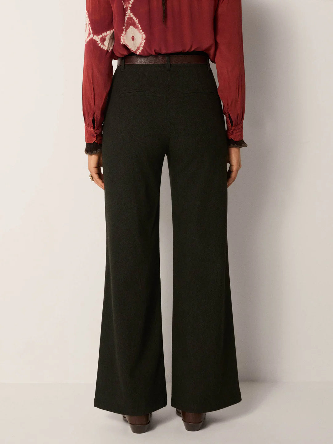 Person wearing a red patterned blouse and dark green wide-leg pants from Maison Hotel