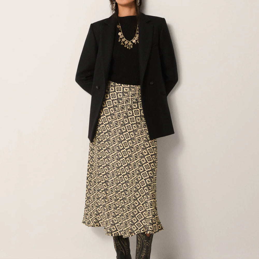 
                      
                        A woman wearing the Irene Skirt from Maison Hotel paired with a black top, black blazer, black cowboy boots and a statement necklace
                      
                    