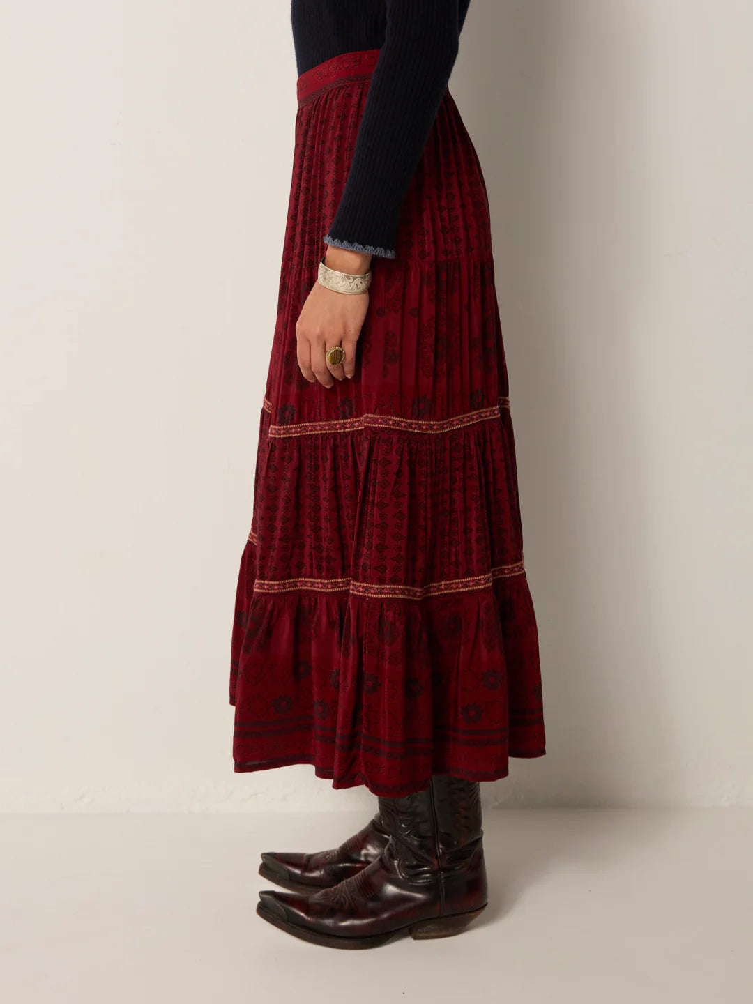 Person wearing a long burgundy skirt with western style boots and a black top