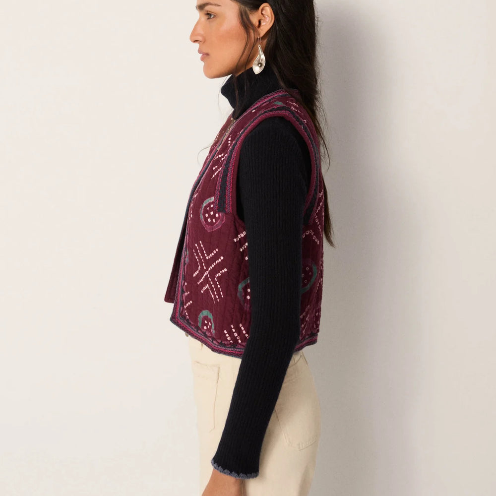 
                      
                        Woman wearing a patterned quilted vest from Maison Hotel over a black long sleeve top
                      
                    