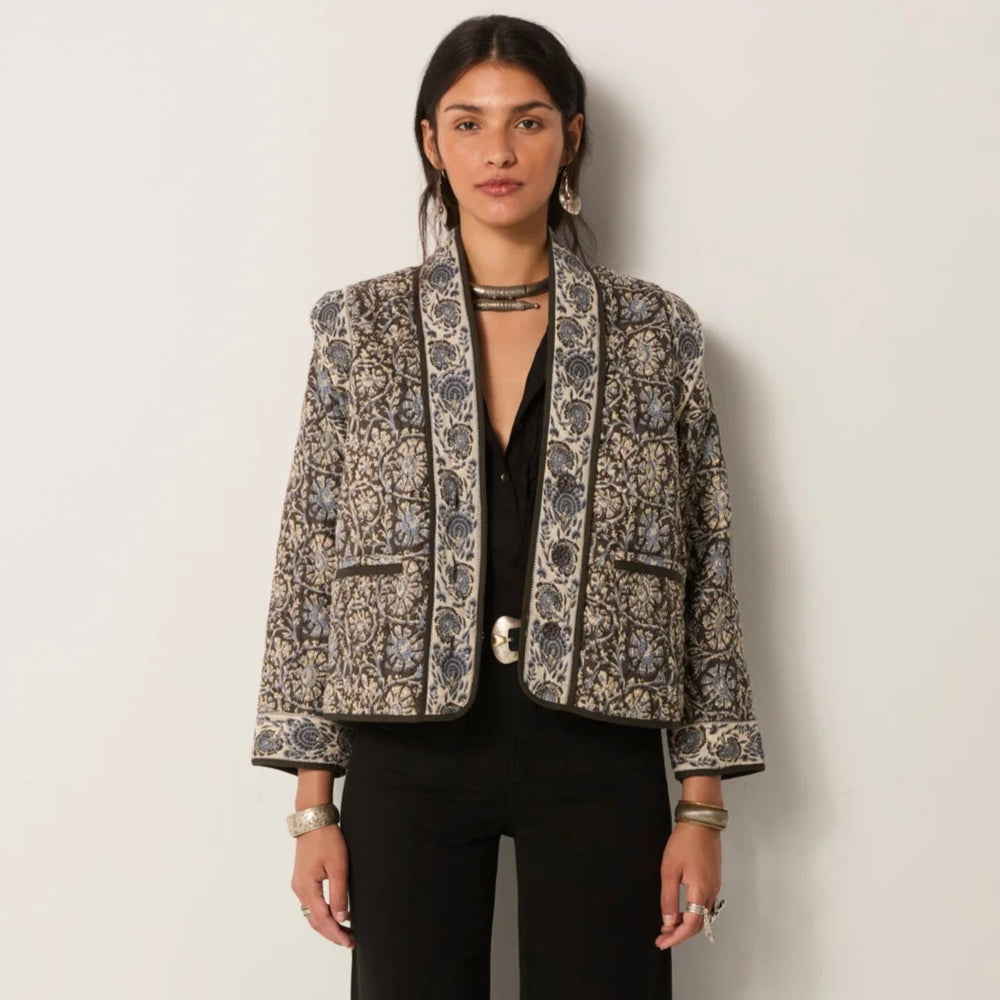Woman wearing a patterned quilted jacket and black pants from Maison Hotel