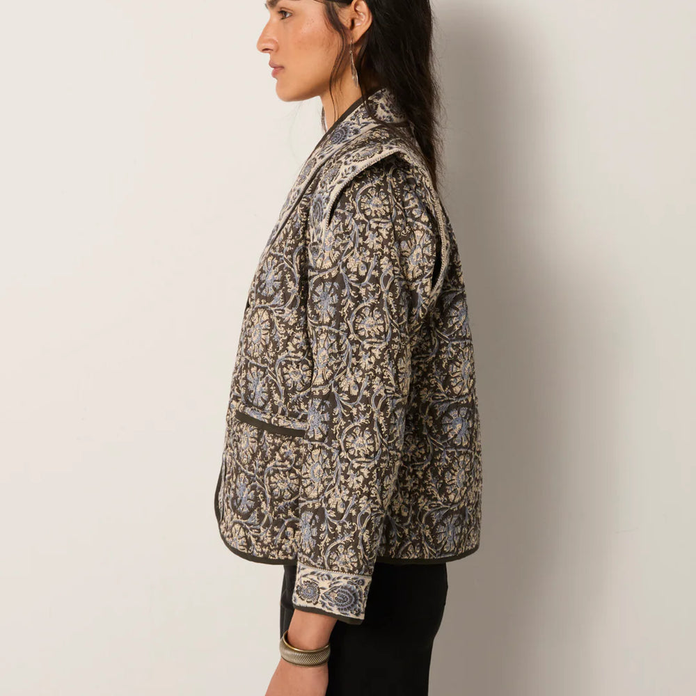 
                      
                        Woman wearing a patterned jacket against a plain background
                      
                    