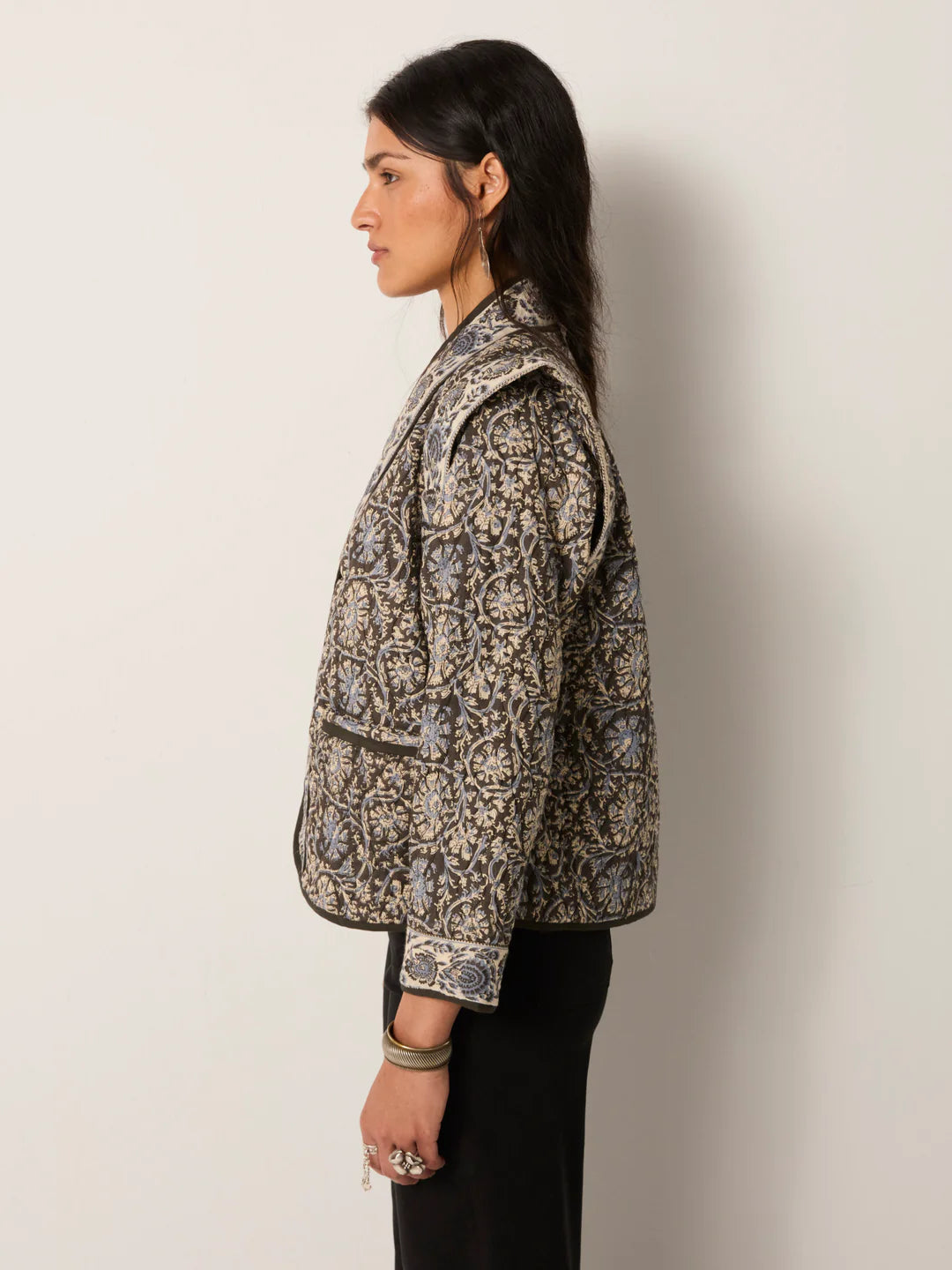 Woman wearing a patterned jacket against a plain background