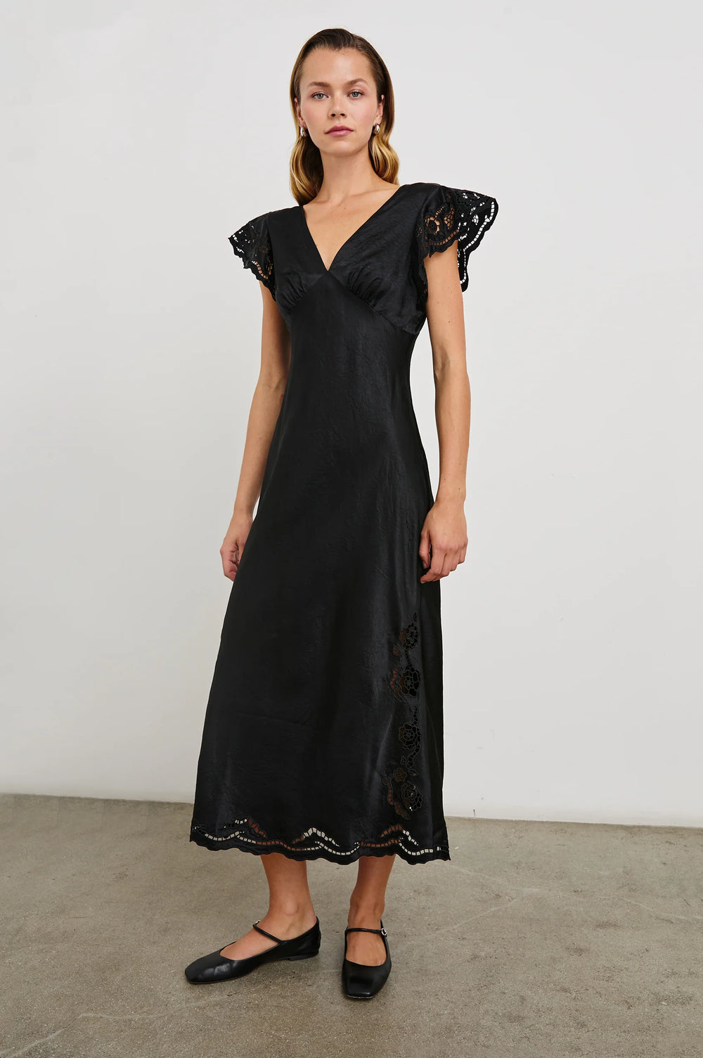 A woman wearing the Black Eyelet McKenna Satin Midi Dress by the brand Rails