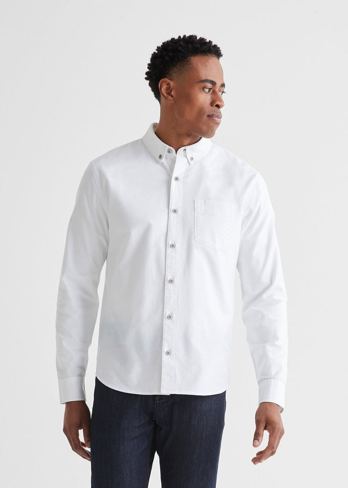 
                      
                        A man wearing the Performance Stretch Button Down in the color white by the brand DUER
                      
                    