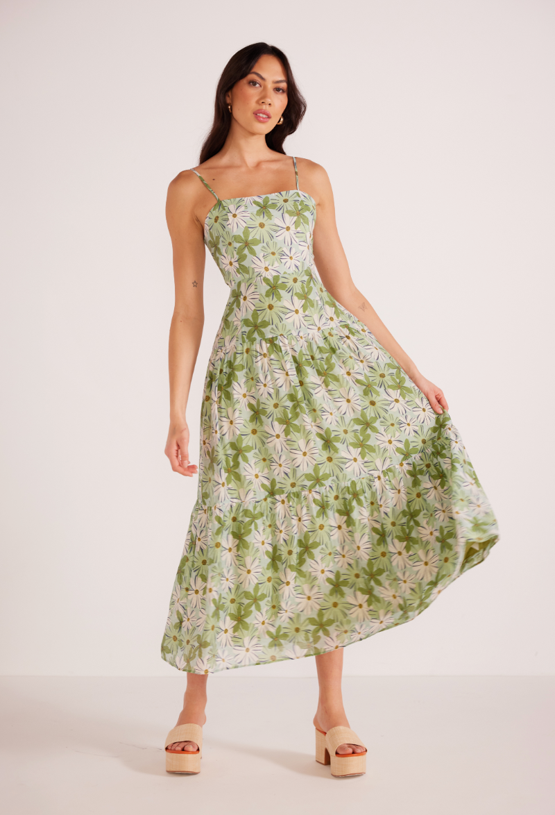 front view of woman wearing a green and white floral print maxi dress with spaghetti straps and a fit and flare silhouette