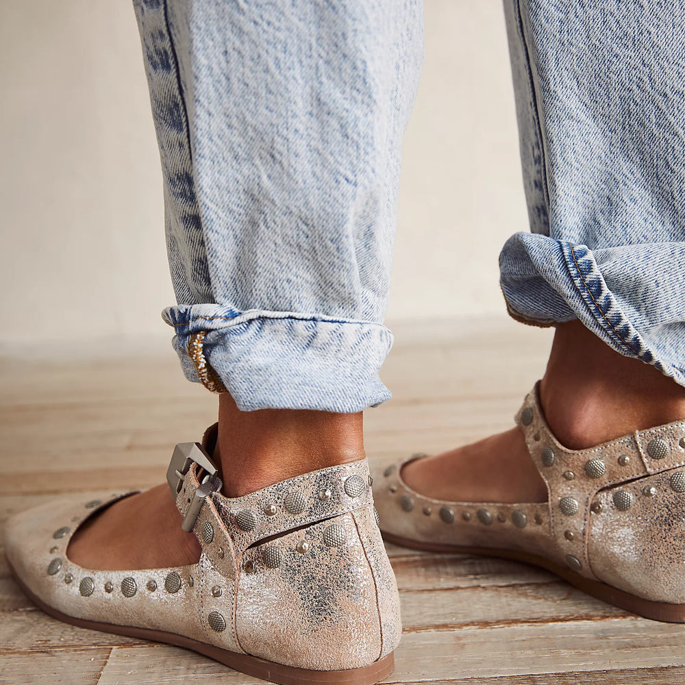 
                      
                        A person wearing the Free People Mystic Mary Jane Flats in Champagne, paired with light wash denim.
                      
                    