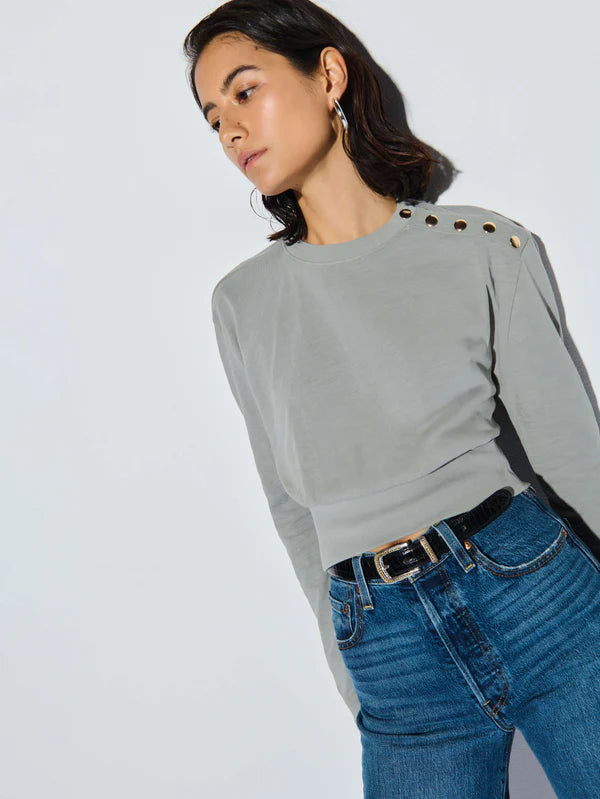 A woman wearing the Dove Grey Monique Top from Nation LTD paired with jeans and black belt