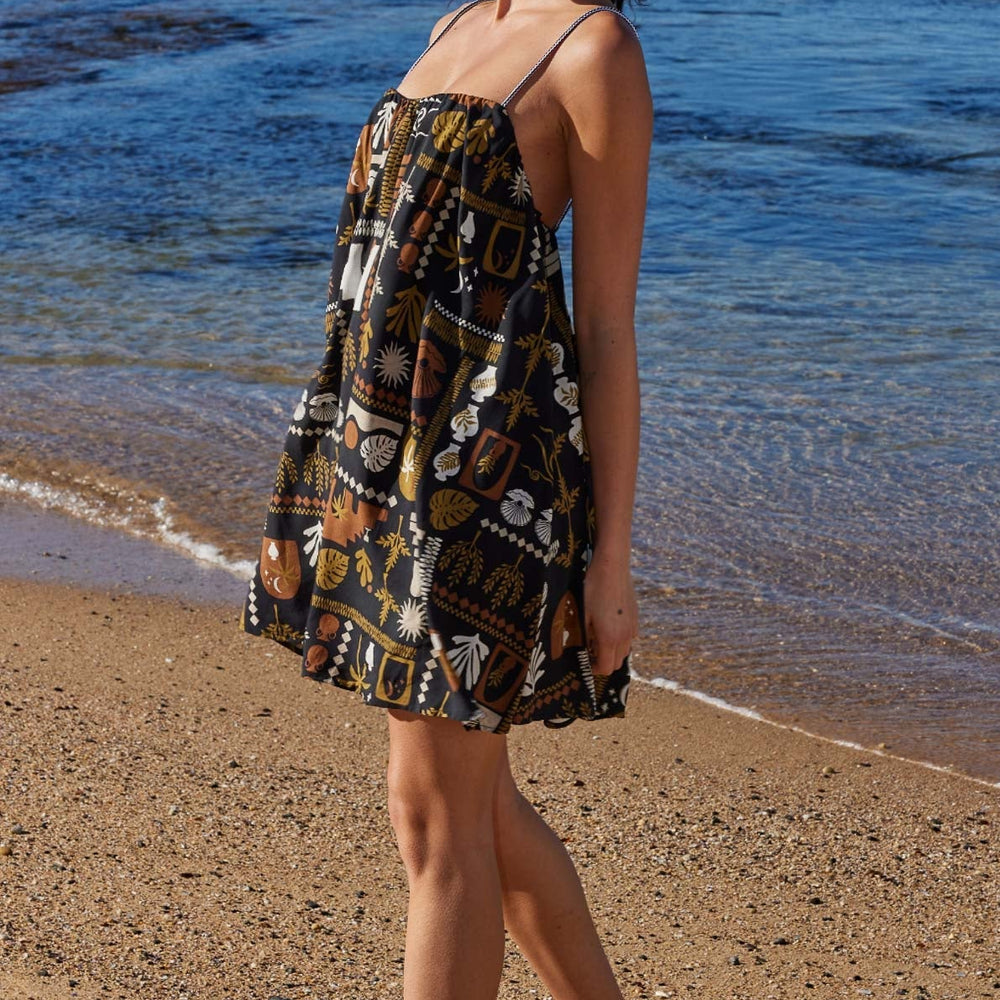 
                      
                        Side view of woman on the beach wearing a printed mini dress with spaghetti straps
                      
                    