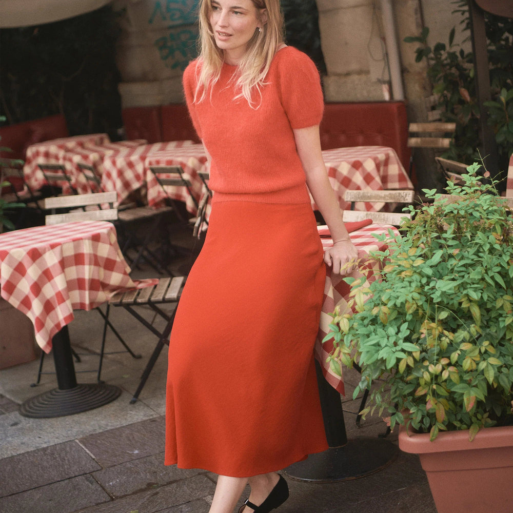A woman wearing the Marine Layer Natalia Circle Skirt with a red sweater
