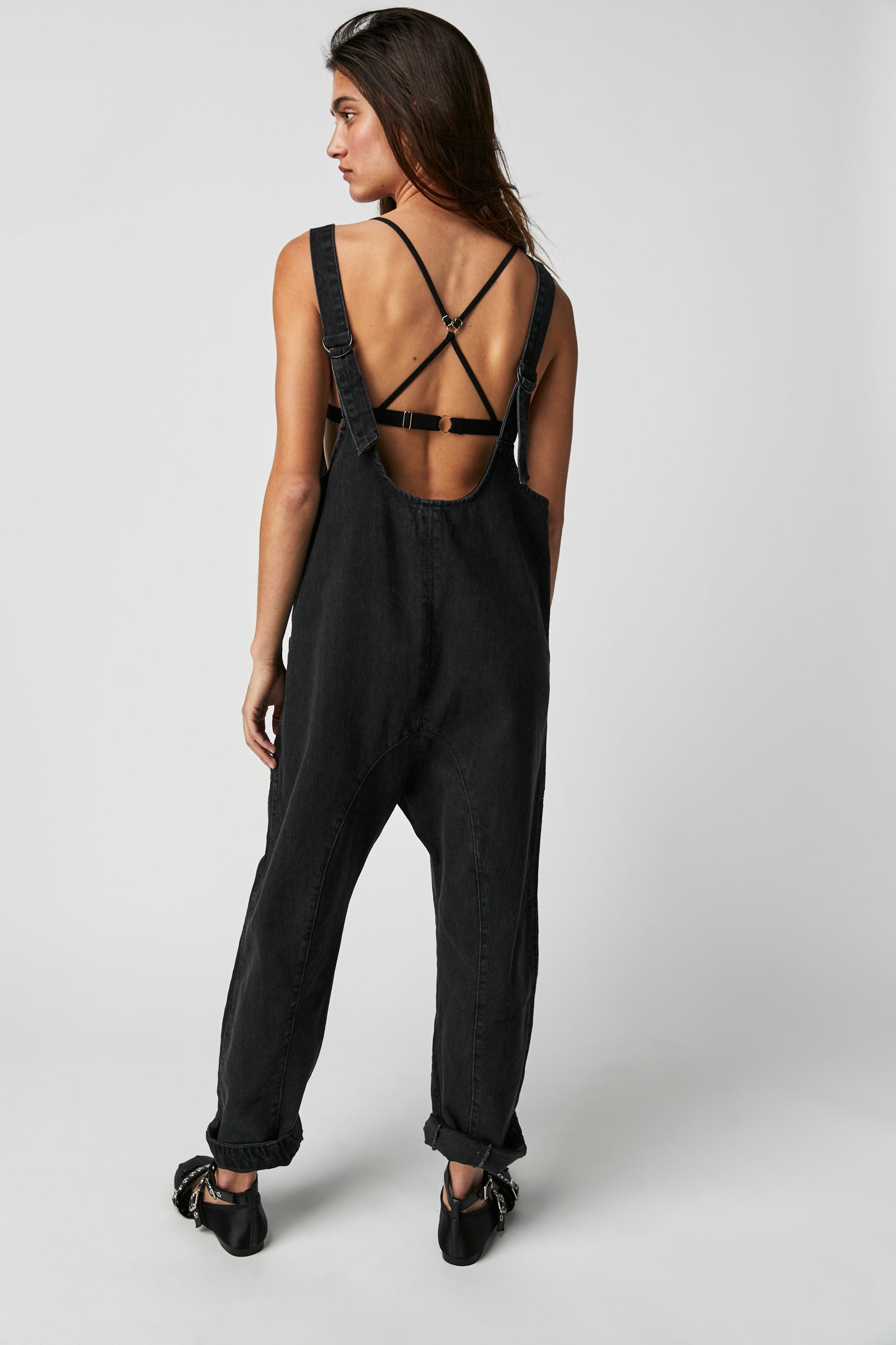 Back view of a woman wearing the Mineral Black High Roller Jumpsuit by Free People