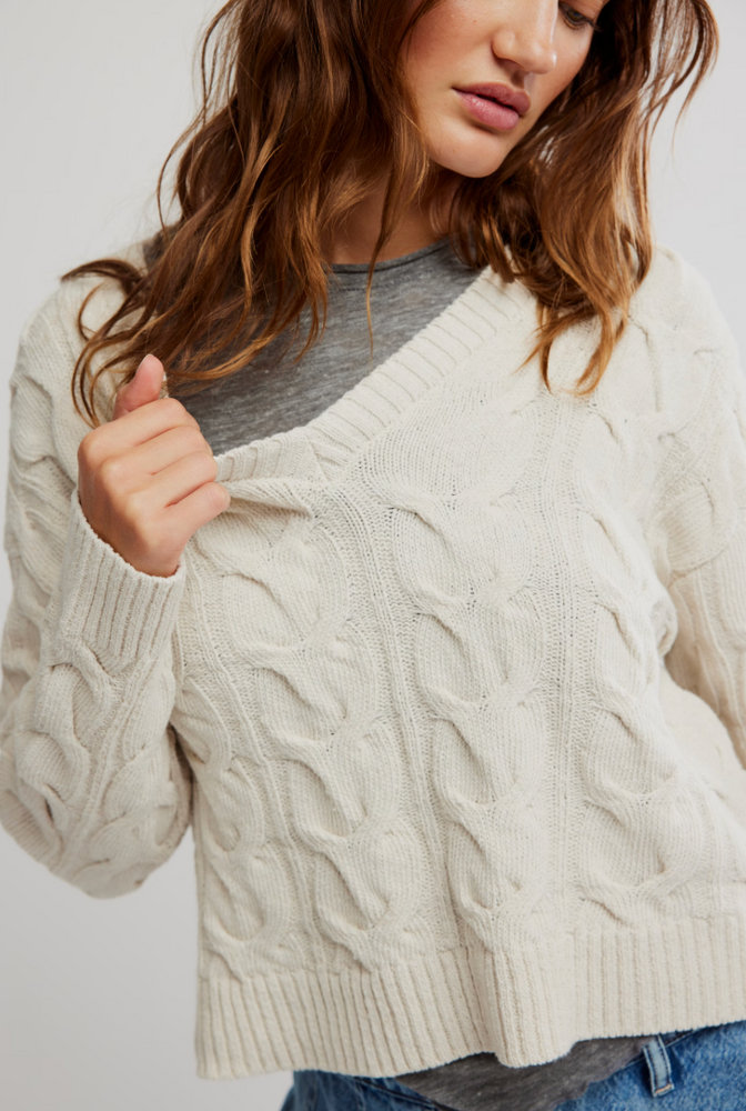 
                      
                        Women's white cable knit v-neck sweater with a relaxed fit. 
                      
                    