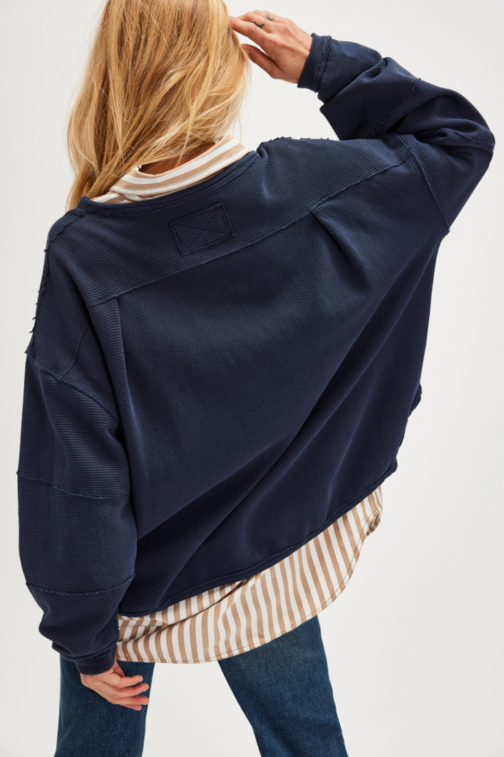 Person wearing a blue long sleeve shirt over a striped shirt 