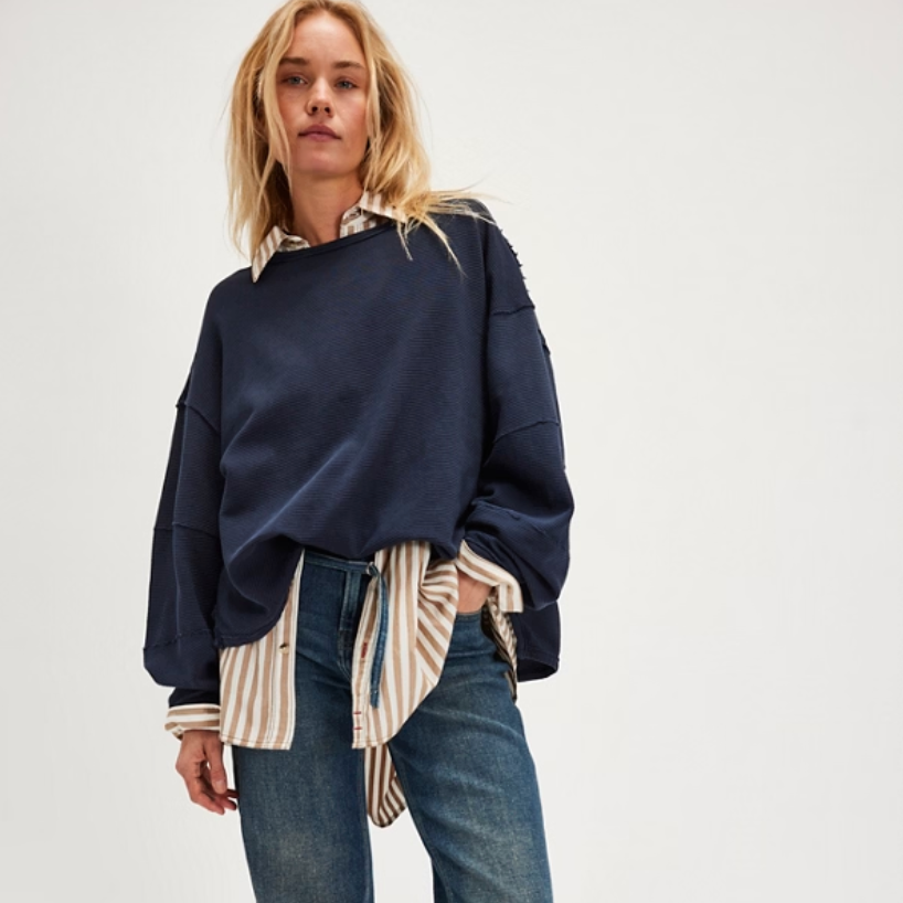 Woman wearing a dark blue sweater from Free People layered over a striped button up shirt