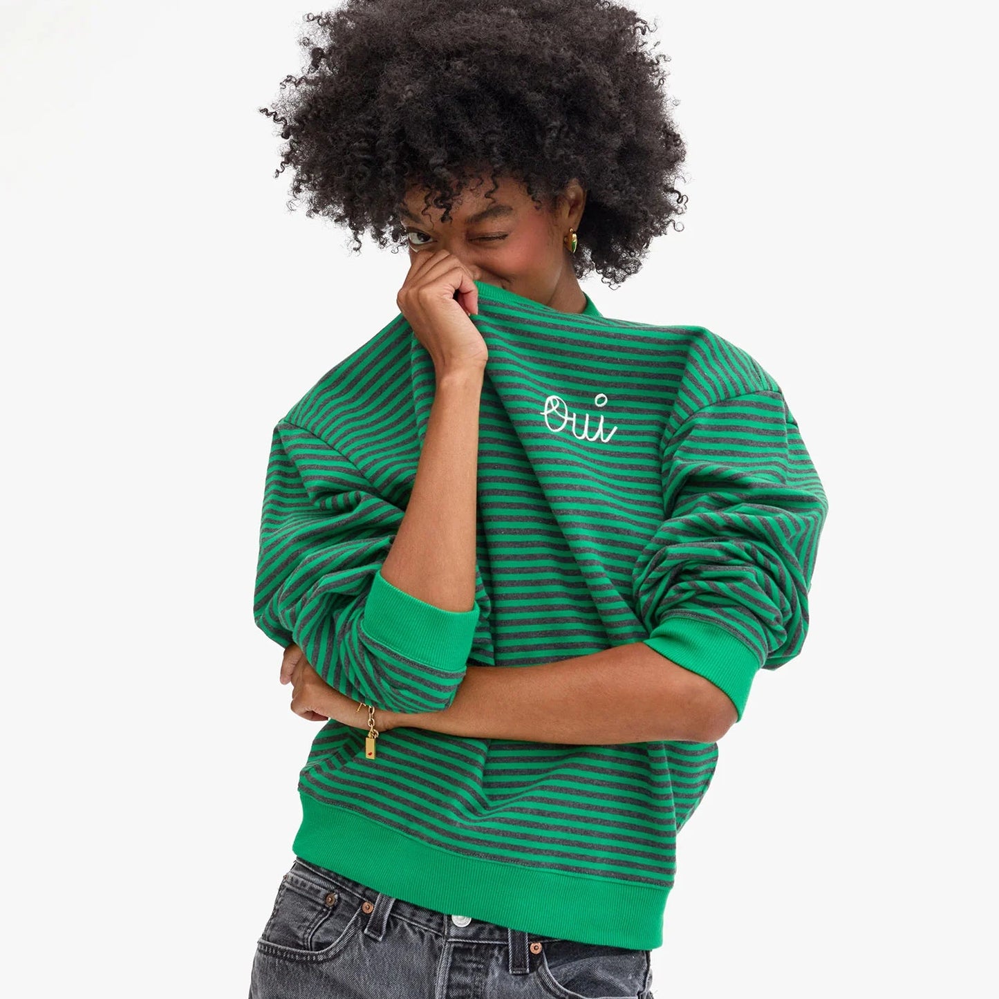 A woman wearing the green striped Clare V. Oversized Sweatshirt