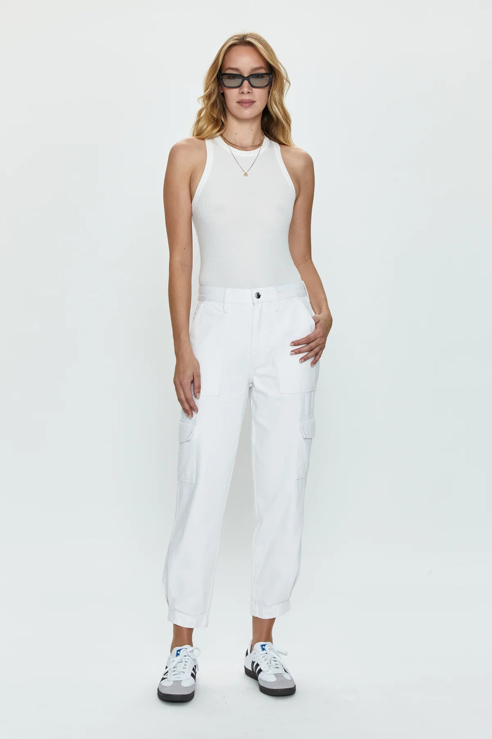 Front view of woman wearing sleek white cargo pants with a high rise and tapered ankle hem