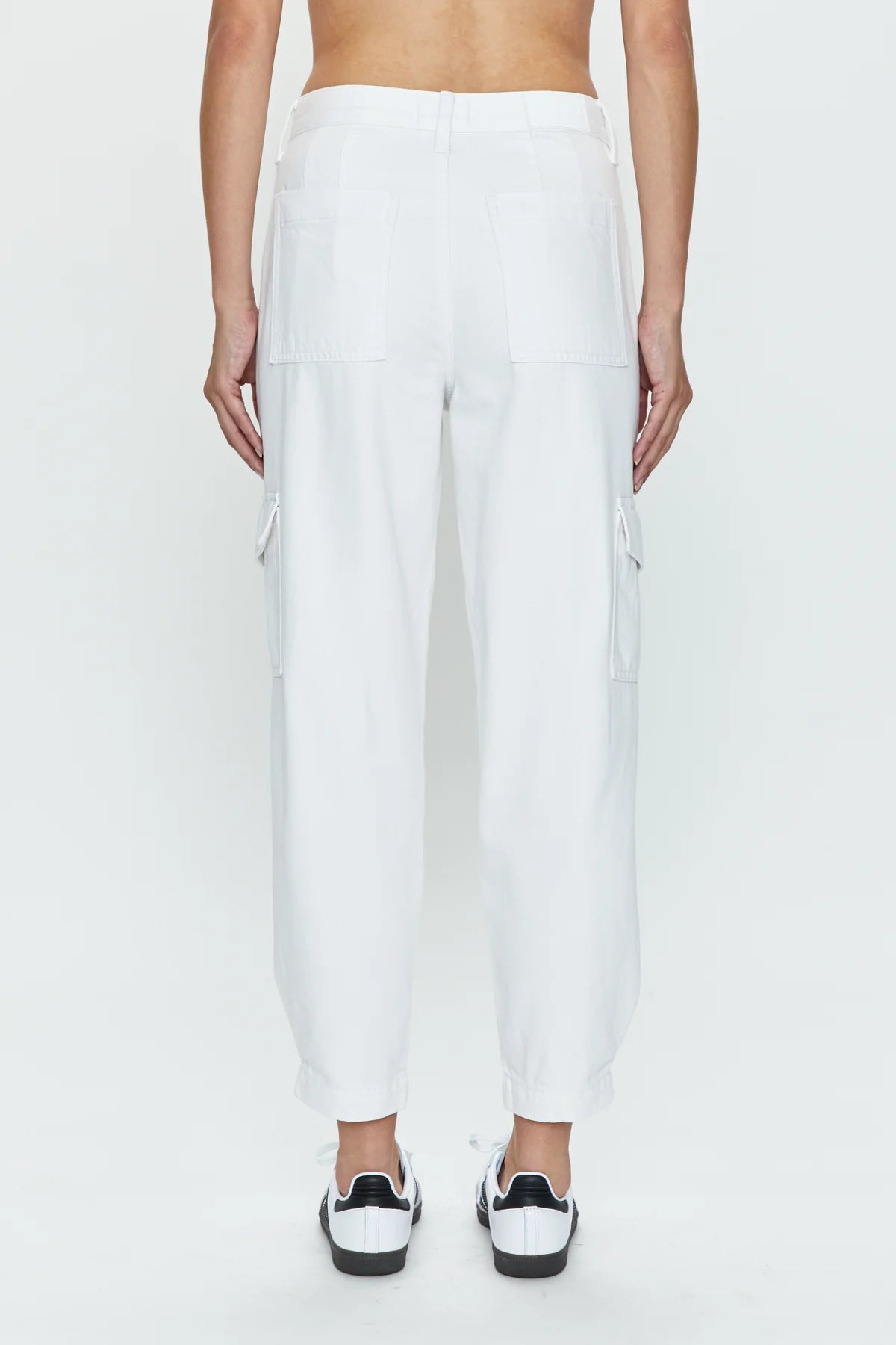 Back view of woman wearing sleek white cargo pants with a high rise and tapered ankle hem