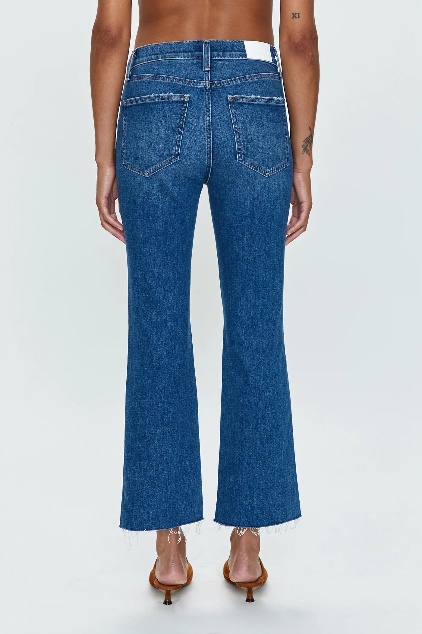 Back view of woman wearing medium wash high rise cropped bootcut jeans by Pistola