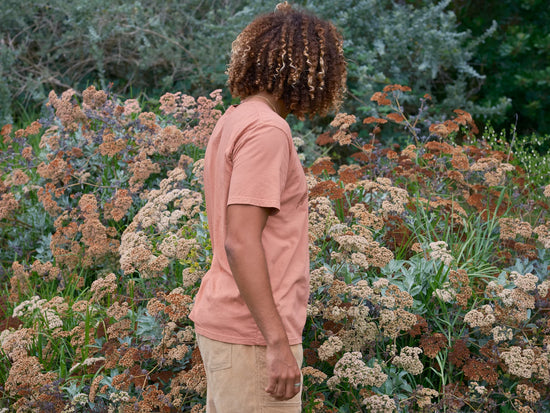 side view of man looking at flowers while wearing the short sleeve Pelican Tee