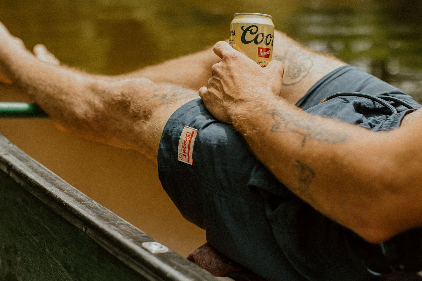 Man sitting on a boat with a beverage while wearing the Navy Yuma Light Shorts by the brand Seager