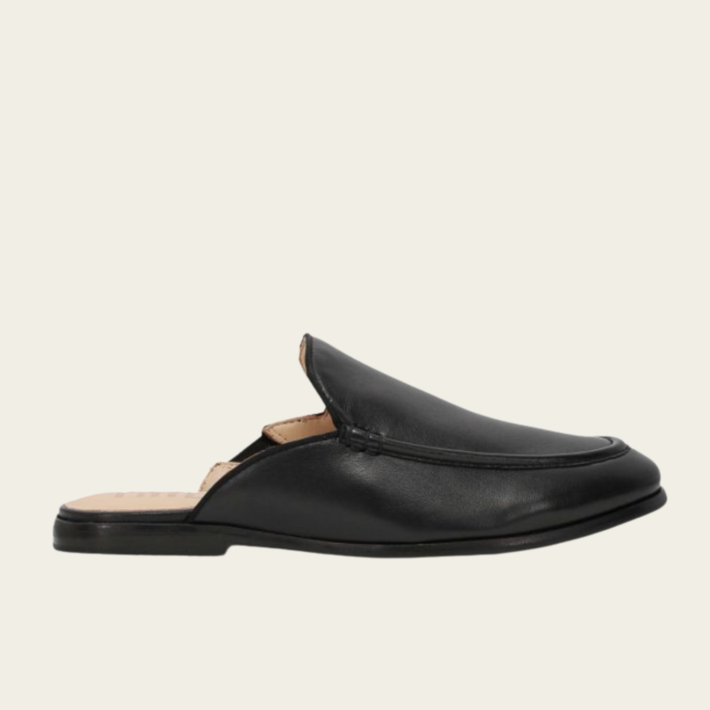 Black slip-on loafer on a beige background
