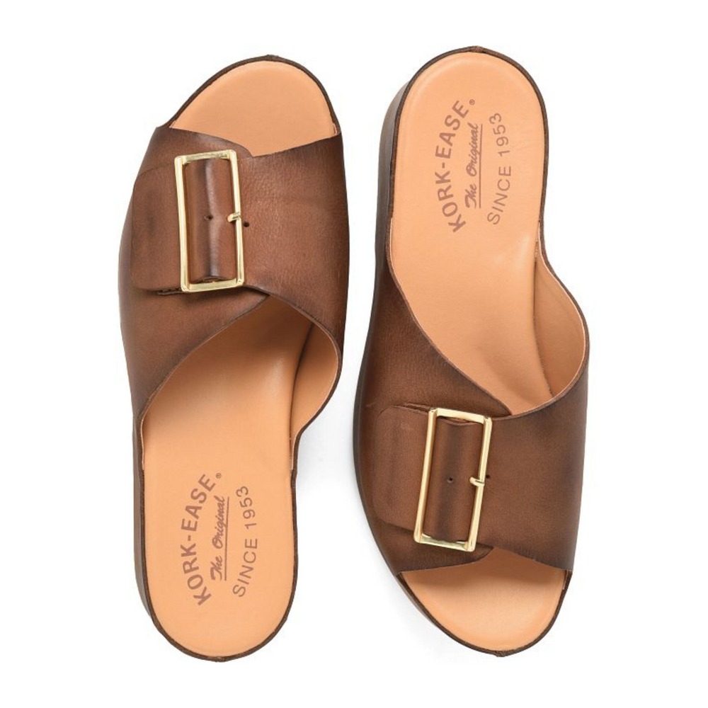 
                      
                        A pair of brown slide sandals with a gold buckle details and visible Kork-Ease branding
                      
                    