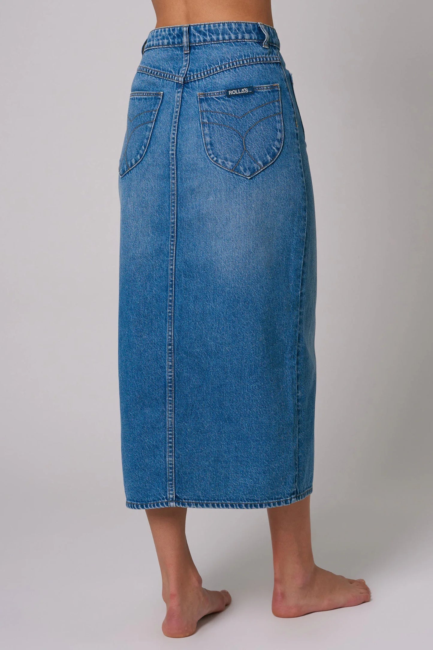 Back view of a medium wash denim midi skirt with two back pockets