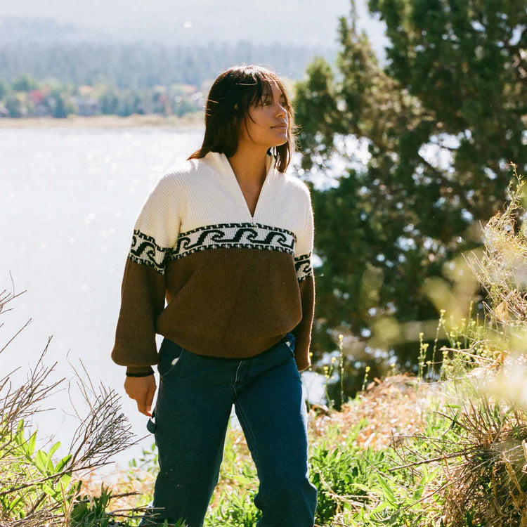 A woman walking in nature while wearing the Roark Fjord Sweater