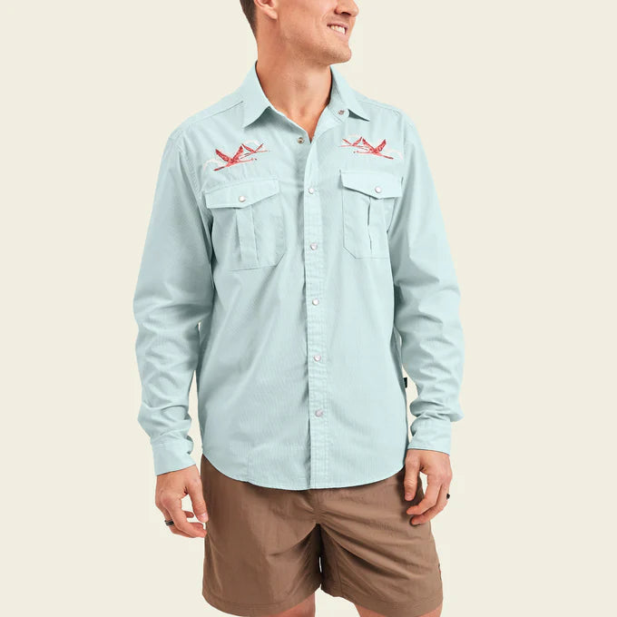 Front view of man wearing a light blue long sleeve snap button up shirt with flamingo embroidery at the chest