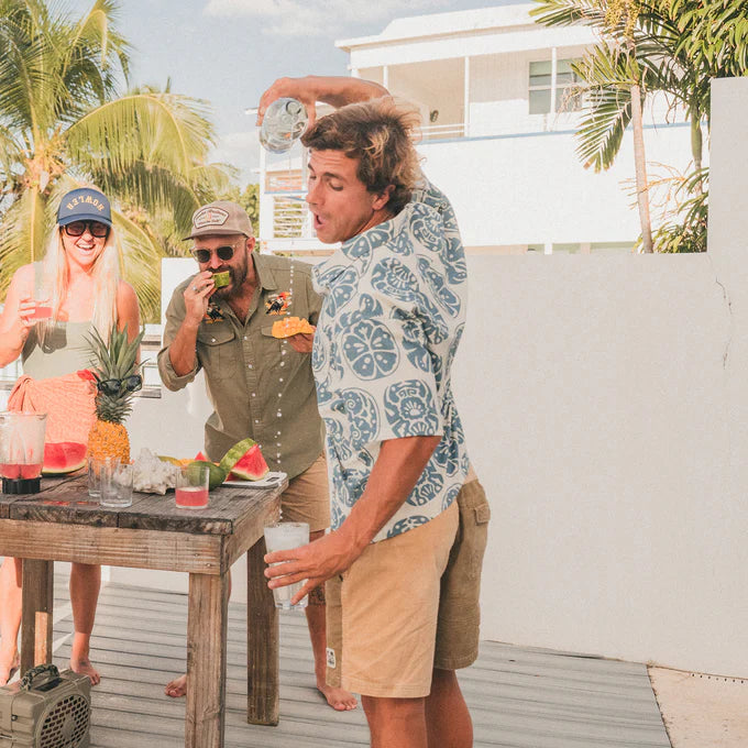 Man outside pouring a drink wearing the Howler Bros Monoloha Shirt in the print Sea Idols