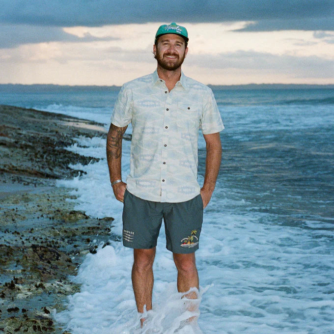 Front view of man wearing the San Gabriel Short Sleeve Button up shirt by Howler bros while standing in the ocean