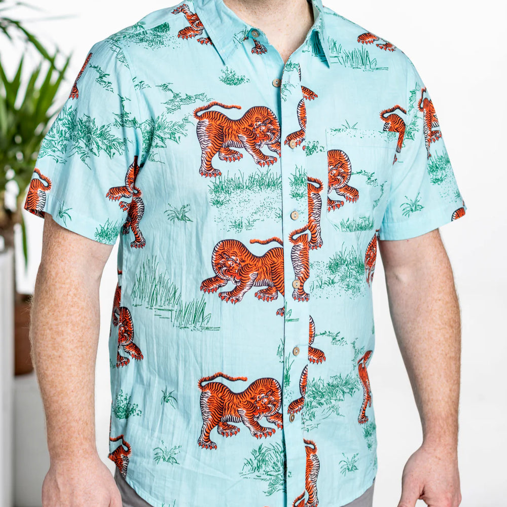 
                      
                        This men's short sleeve button down shirt features a light blue base with a custom One World Brothers tiger print throughout. 
                      
                    