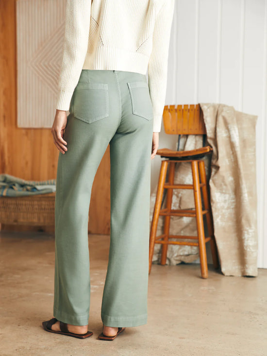 Back view of woman wearing sage color stretch terry pocket pants by Faherty