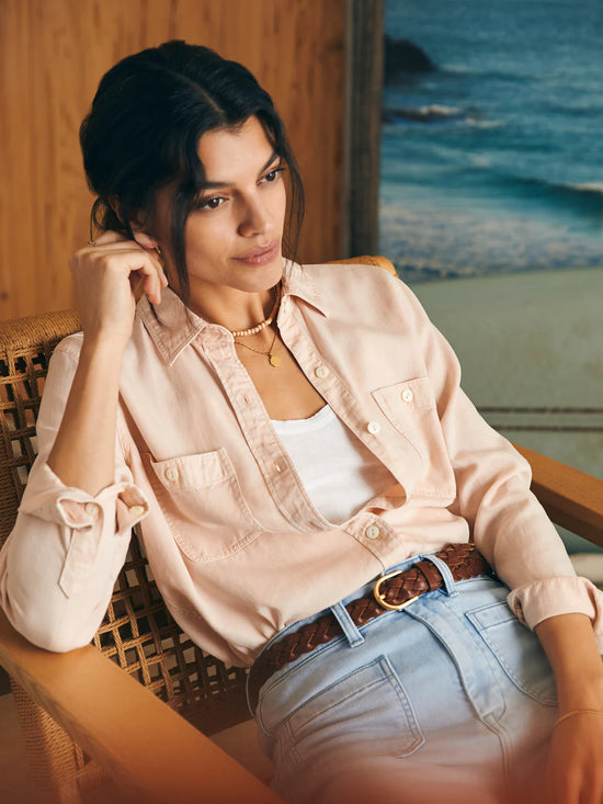 Woman wearing a peach color chambray button up shirt tucked into her jeans