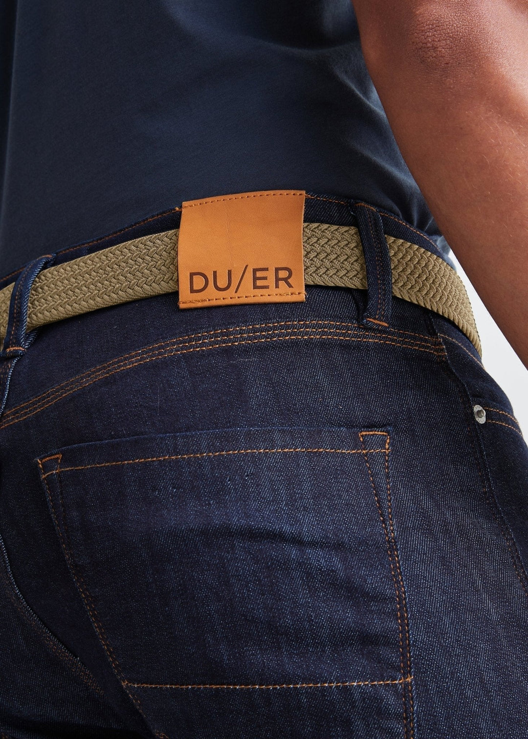 Back view of man wearing the sand color Performance Stretch Belt by DU/ER