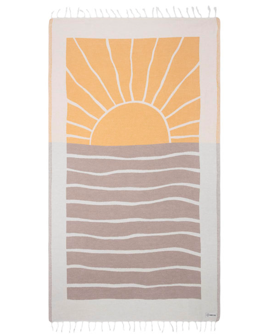 unfolded view of a sand cloud beach towel with a sun and sea inspired design and tassels at the ends