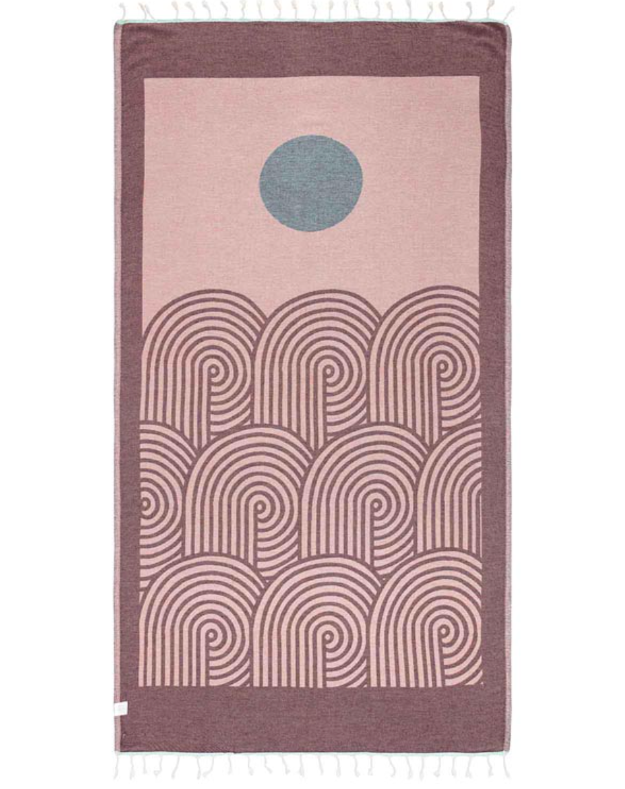 reverse color unfolded view of a sand cloud beach towel with an artful sun and sea inspired design and tassels at the ends