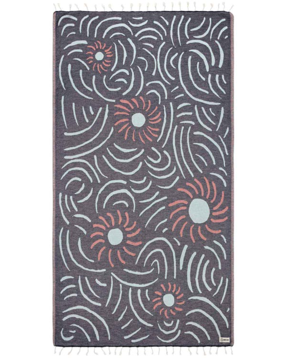 unfolded view of a navy beach towel featuring artful flower and line designs and tassels at the end