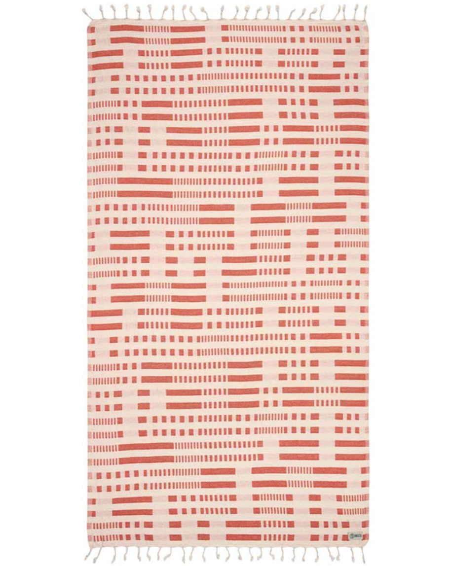 Unfolded view of the Canggu Beach Towel by Sand Cloud featuring a line and dash design throughout and tassels at the ends