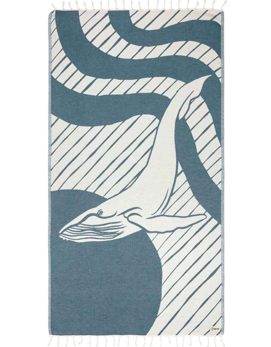 Unfolded view of a beach towel with a whale design and tassels at the ends