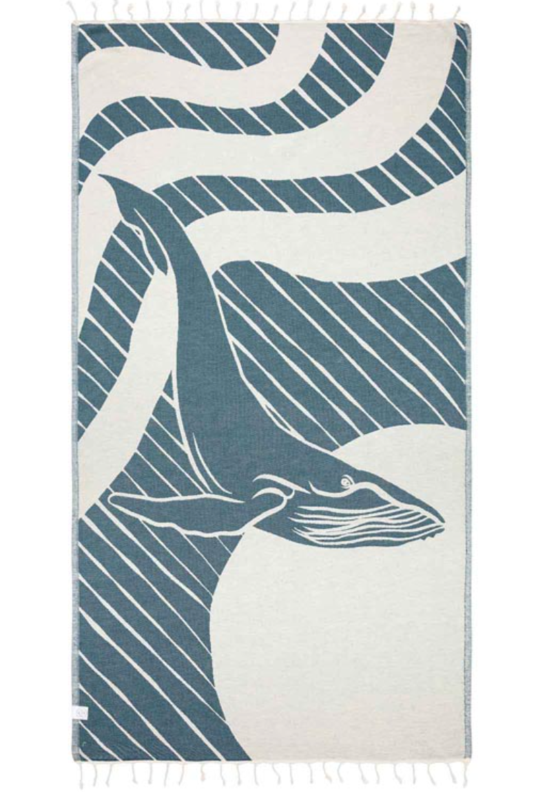 Unfolded view of the reverse side of a beach towel with a whale design and tassels at the ends