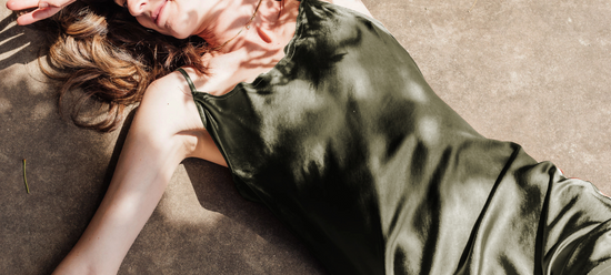 Woman lying on the ground wearing the green Sawyer midi slip Dress by Harbour Thread. 