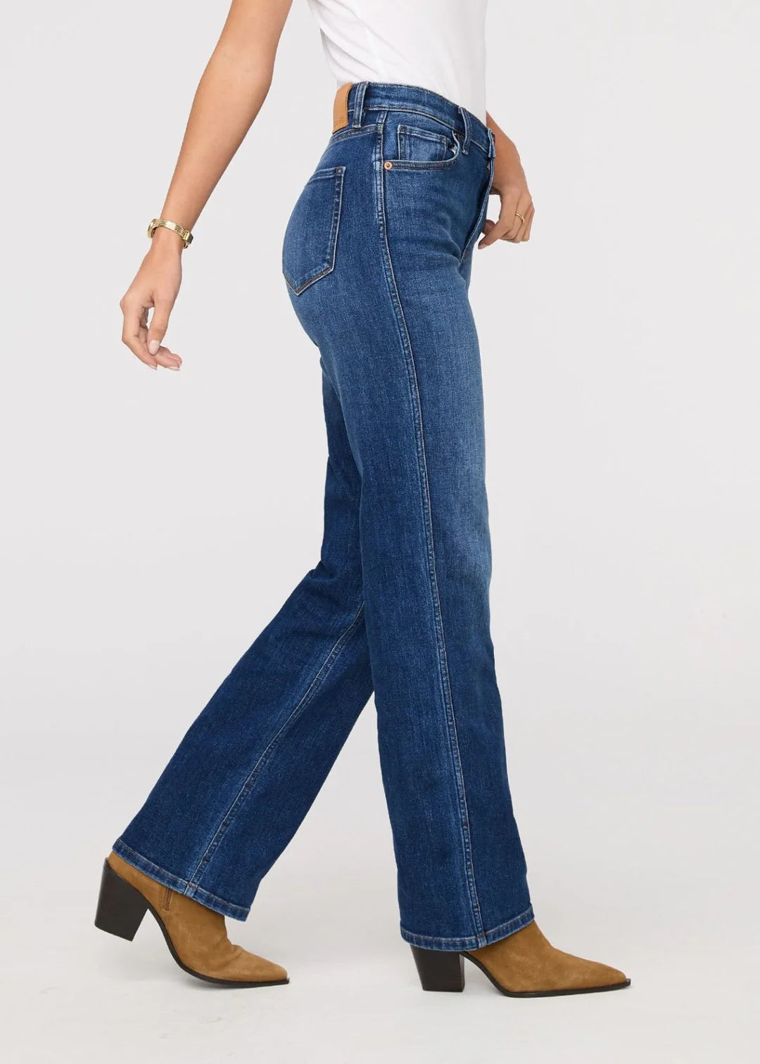 Person wearing blue jeans and brown shoes on a white background