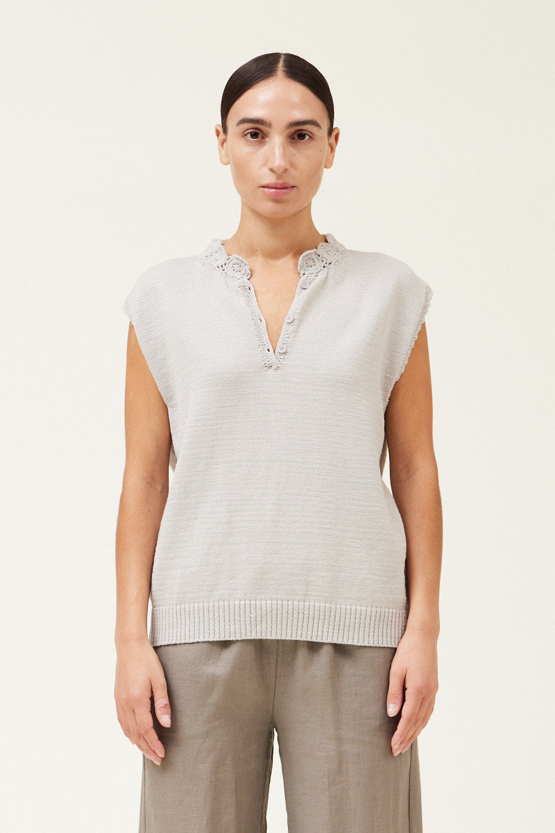 Front view of a woman wearing a sleeveless crochet trim sweater top 