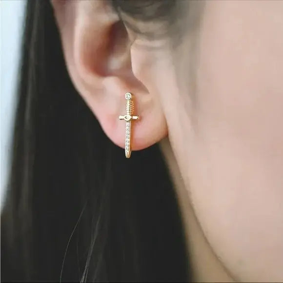 A person wearing the Dagger Stud Earrings by Tramps + Thieves