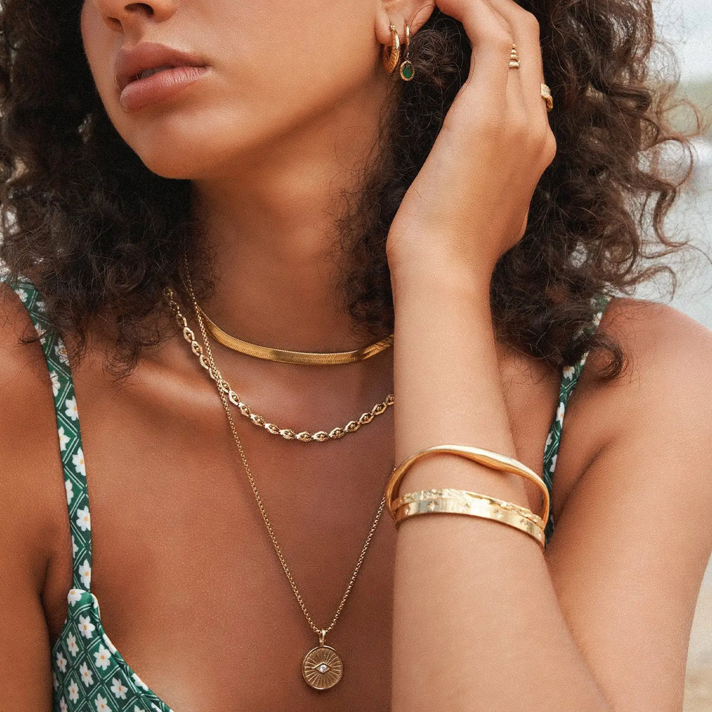 
                      
                        Woman wearing the Totti Gold Necklace by Arms of Eve layered with other necklaces
                      
                    