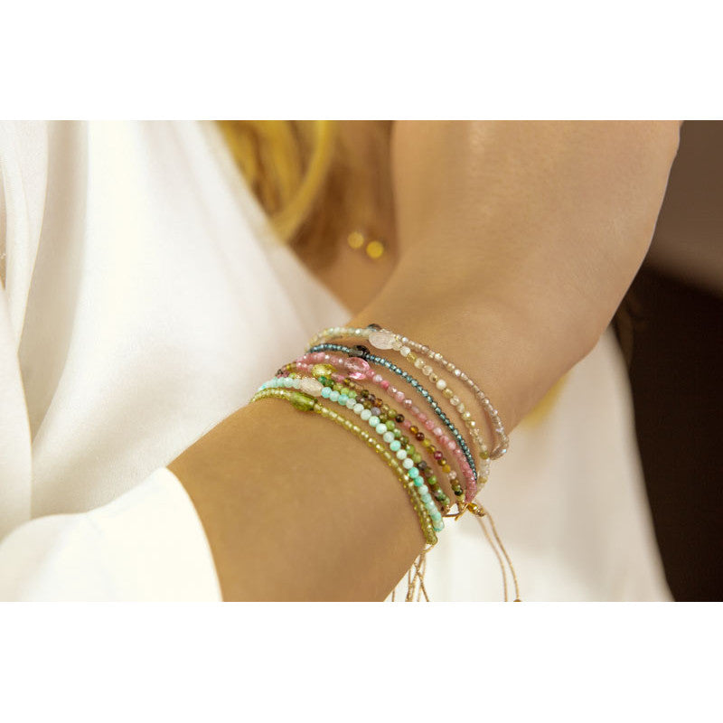 Person wearing the Pink Tourmaline Multi Dolly Bracelet by Sophie Deschamps Bijoux layered with several other gemstone bracelets