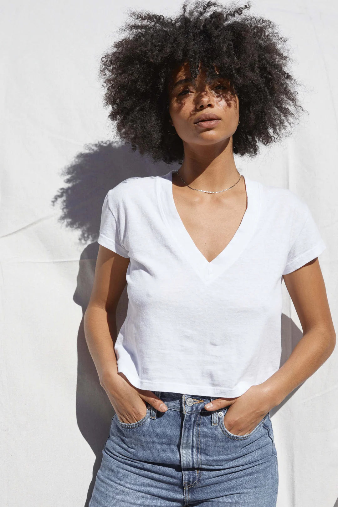 A woman wearing the White Alanis V-Neck Tee by the brand Perfect White Tee