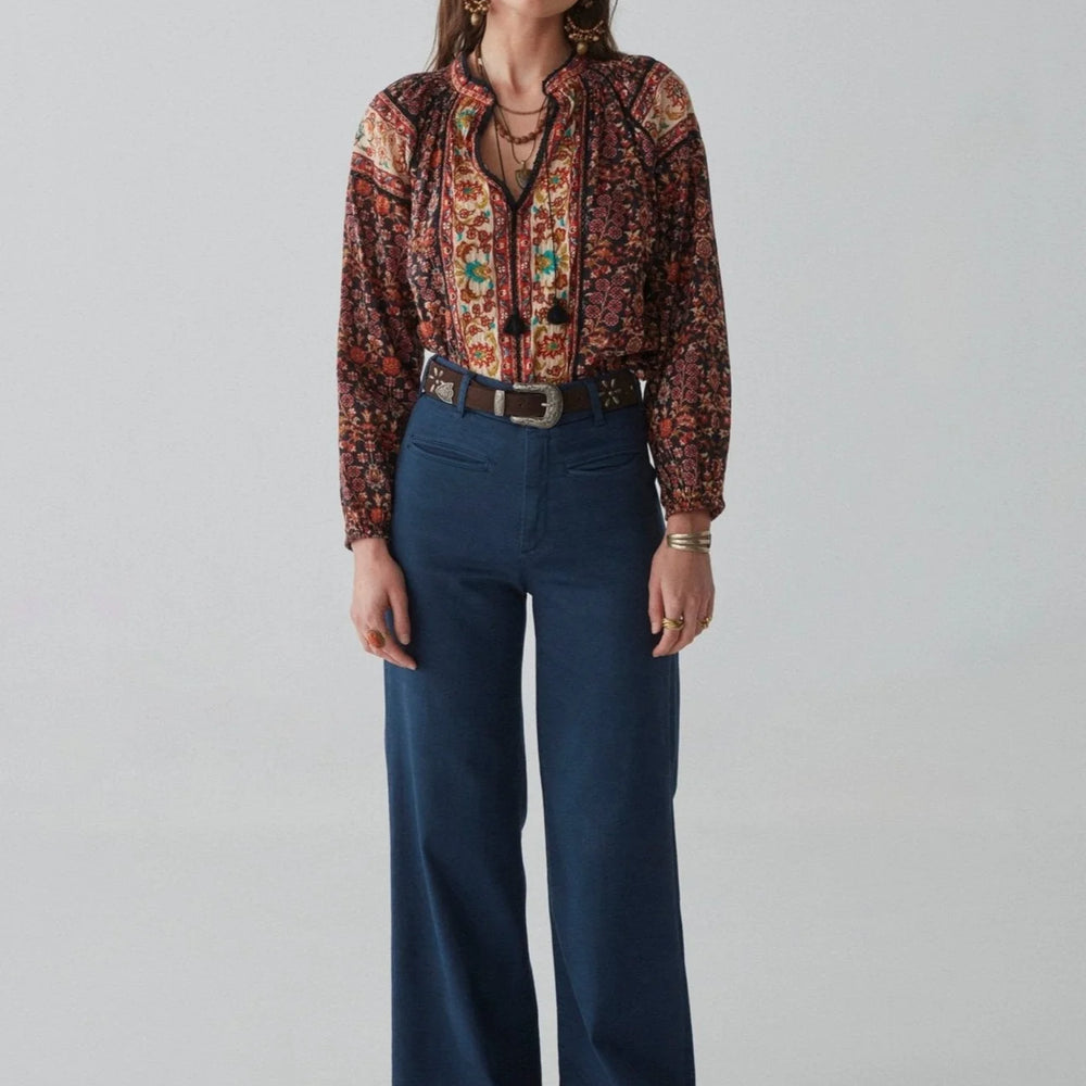 
                      
                        An outfit styled with the Audrey Blouse by Maison Hotel, tucked into dark blue trousers with a belt
                      
                    