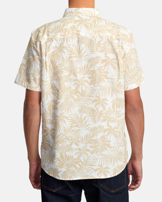 Back view of man wearing a short sleeve button up shirt with a light khaki botanical print throughout